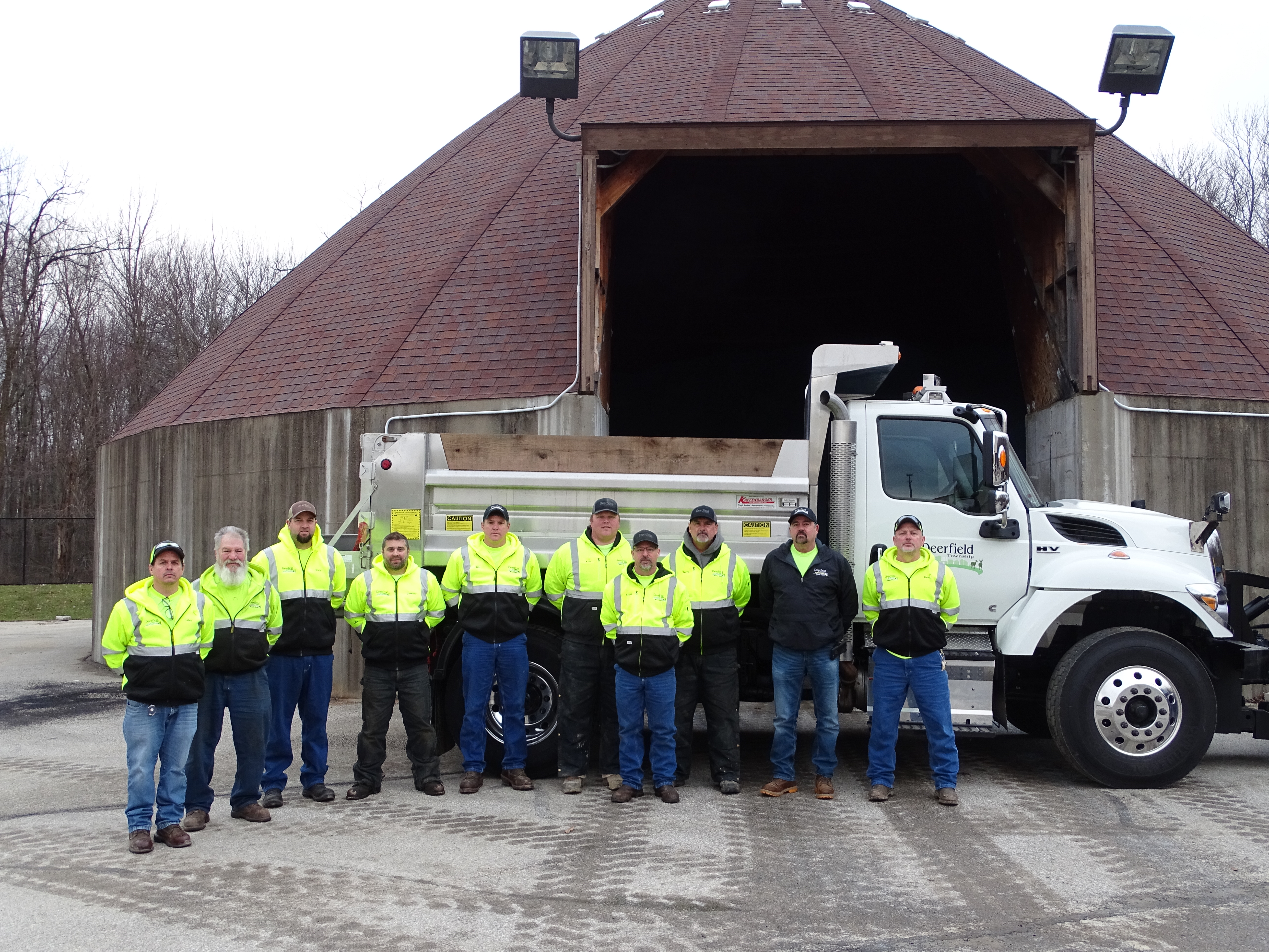 Workers in front of salt barn and snow plow